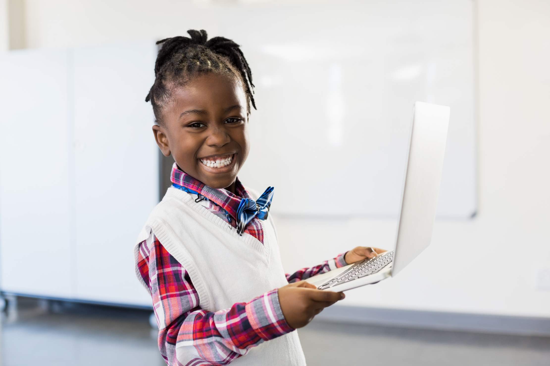 Happy schoolgirl using a laptop in the classroom