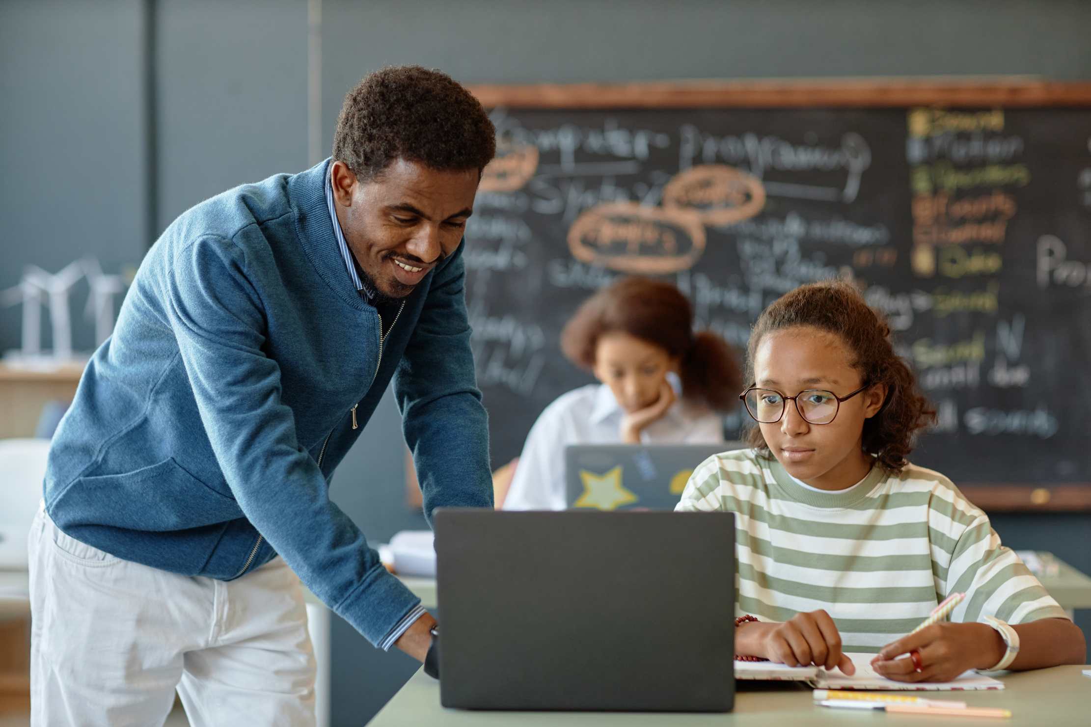 Teacher helping a student with work on a laptop